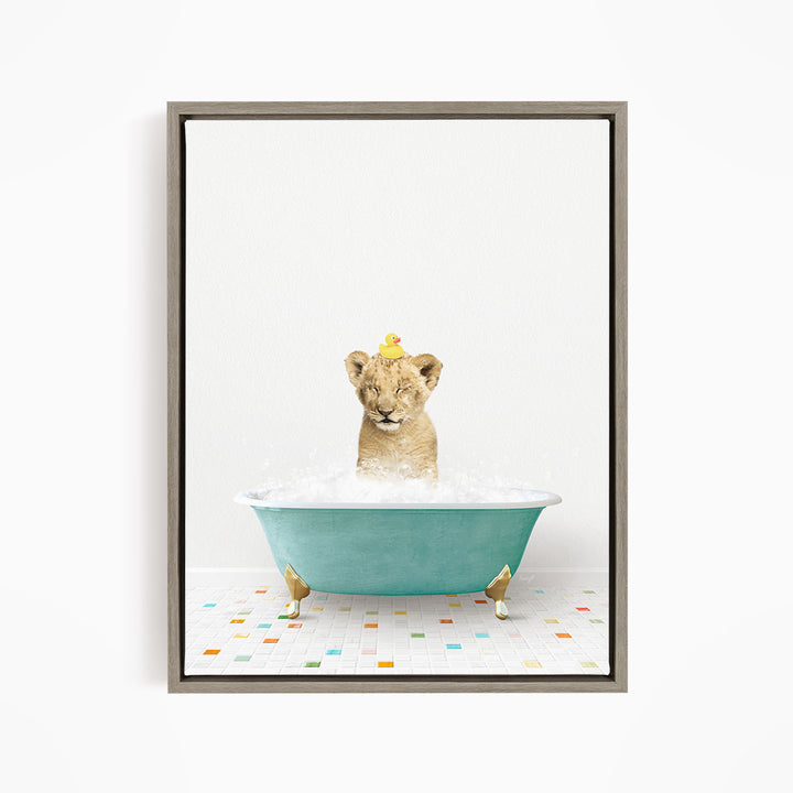 A young lion cub sitting in a blue bathtub filled with bubbles, with a yellow rubber duck perched on its head.