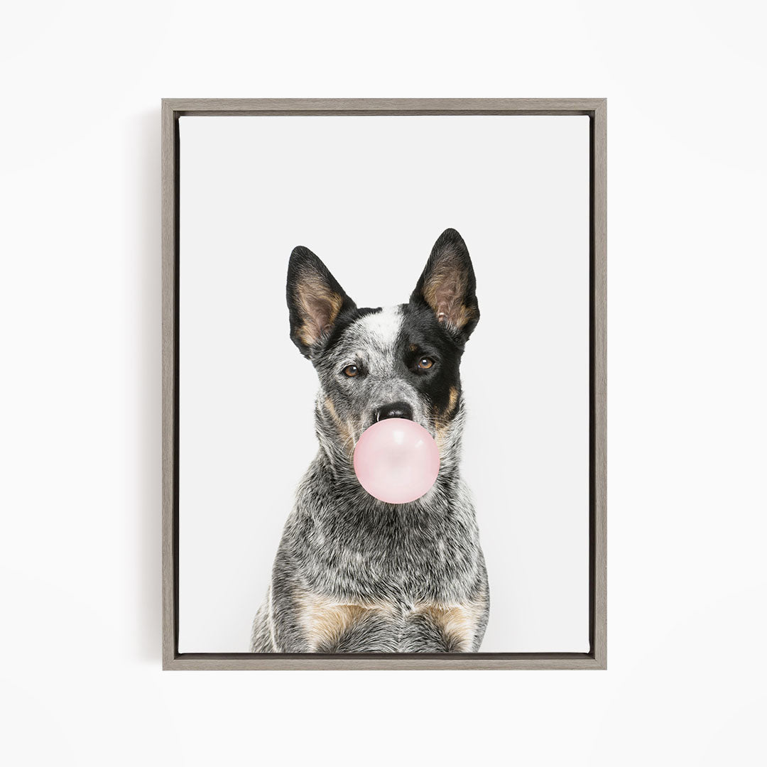 A black and white dog is blowing a pink bubble with its mouth, creating a playful and whimsical scene.