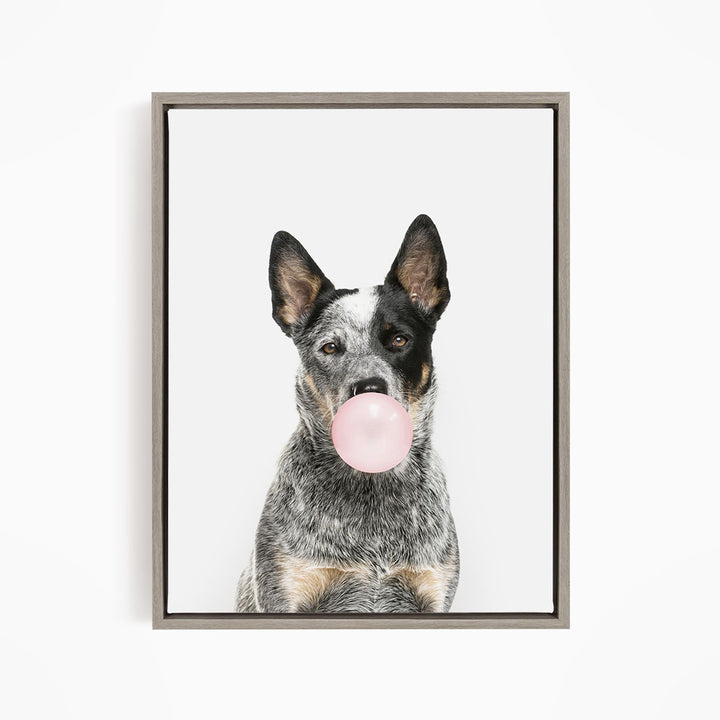 A black and white dog is blowing a pink bubble with its mouth, creating a playful and whimsical scene.