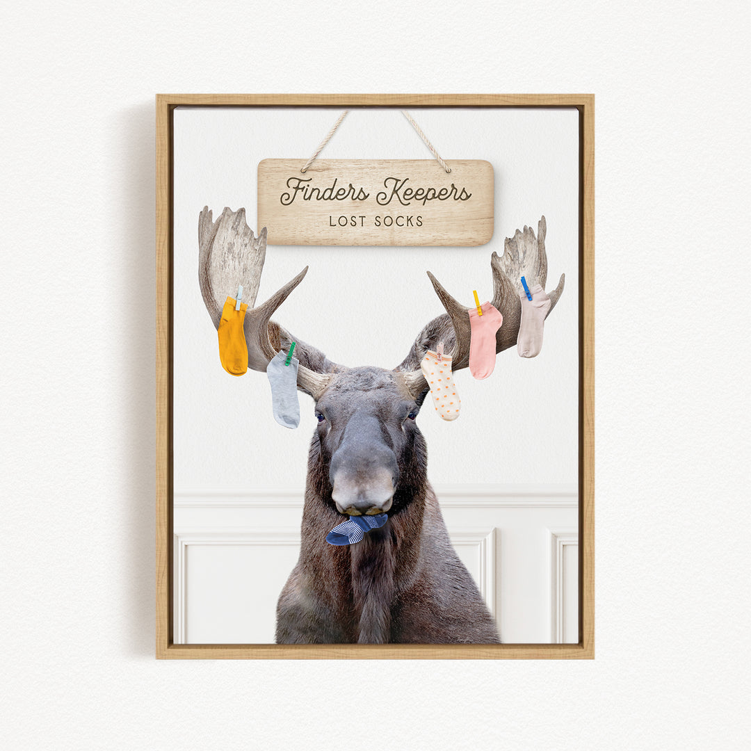 A framed image of a moose with a sign above it that says "Finders Keepers Lost Socks".