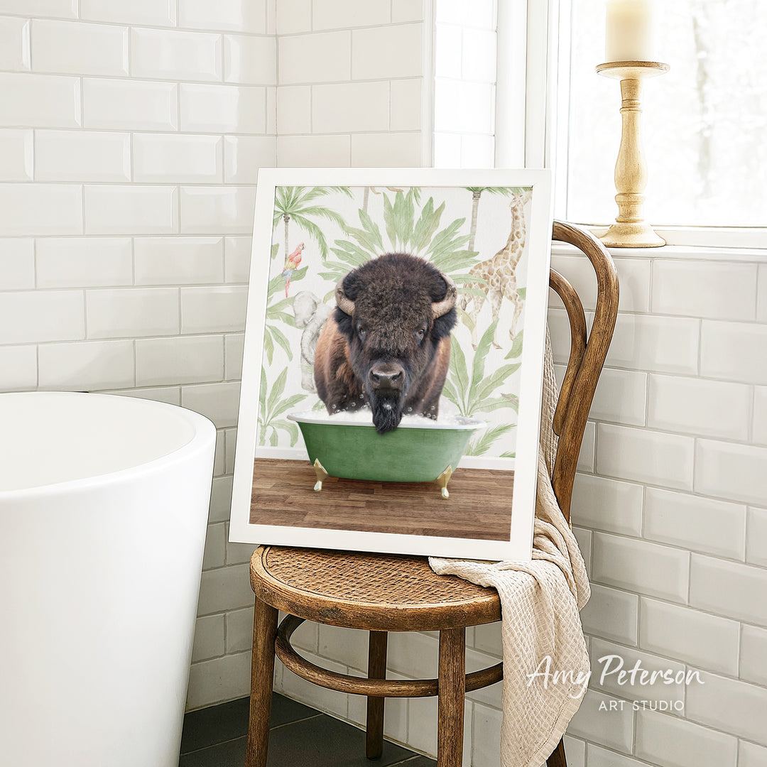 A framed image of a bison in a bathtub is displayed on a wooden chair in a bathroom setting.