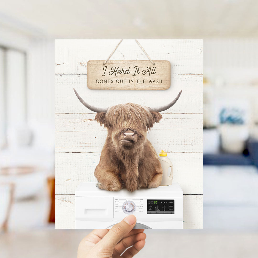 A hand holding a sign with a cartoon image of a horned animal, likely a yak or a yak dog, sitting on top of a washing machine.