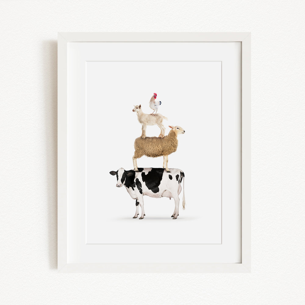 A framed image depicting a cow, sheep, and chicken stacked on top of each other.