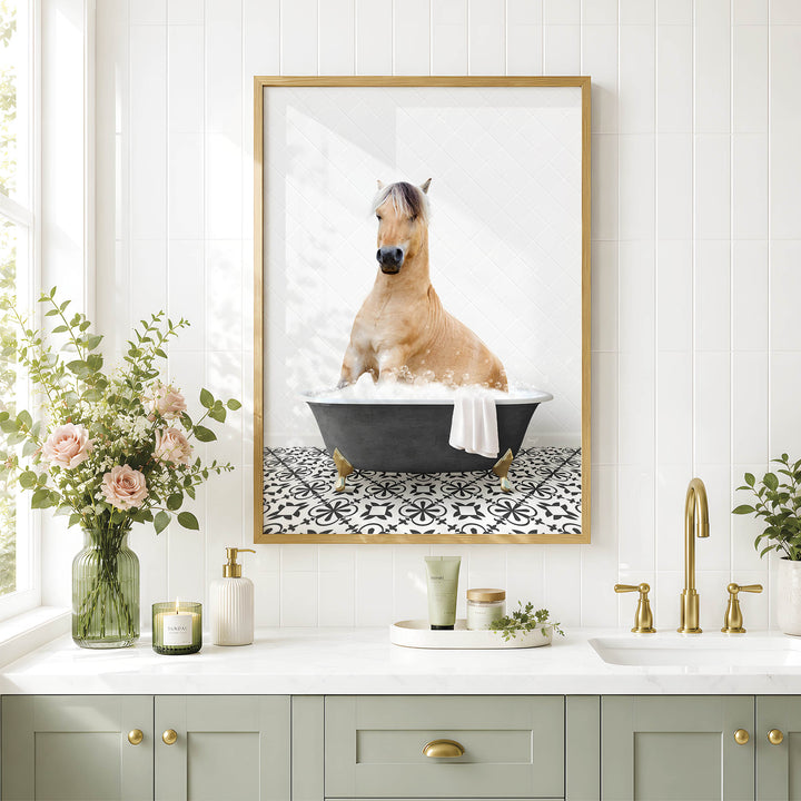 A framed image of a horse sitting in a bathtub, surrounded by flowers and a decorative vase, is displayed on a white tiled wall above a bathroom sink.
