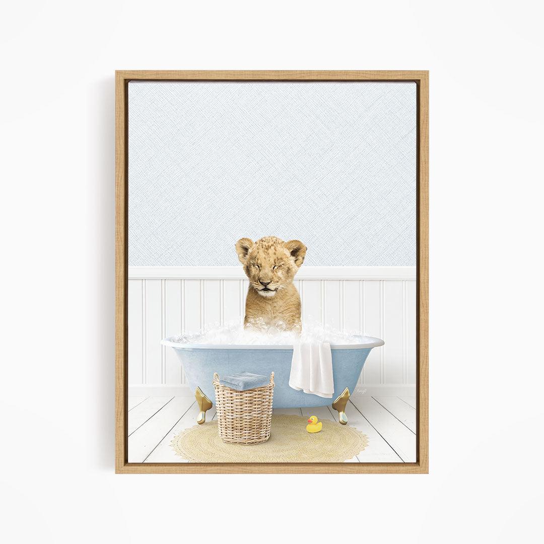 A young lion cub sitting in a blue bathtub filled with water, surrounded by a basket of toys and a yellow rubber duck.