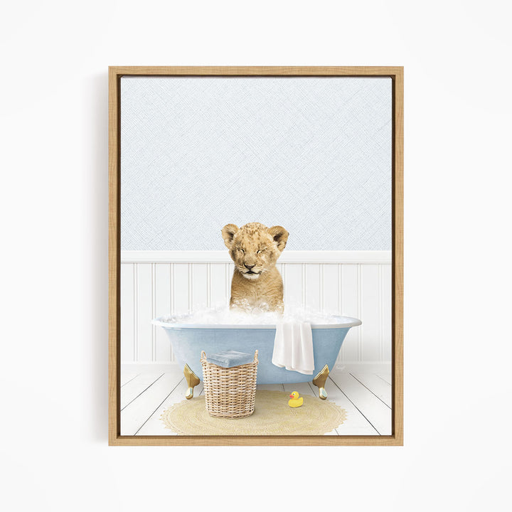 A young lion cub sitting in a blue bathtub filled with water, surrounded by a basket of toys and a yellow rubber duck.