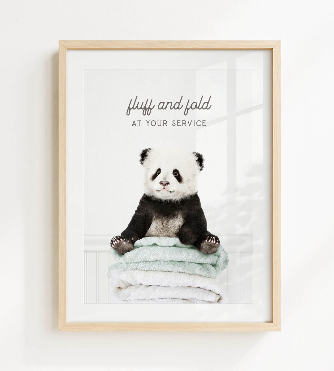 A panda bear sitting on a stack of towels with the text "fluffy and folded at your service" written above it.