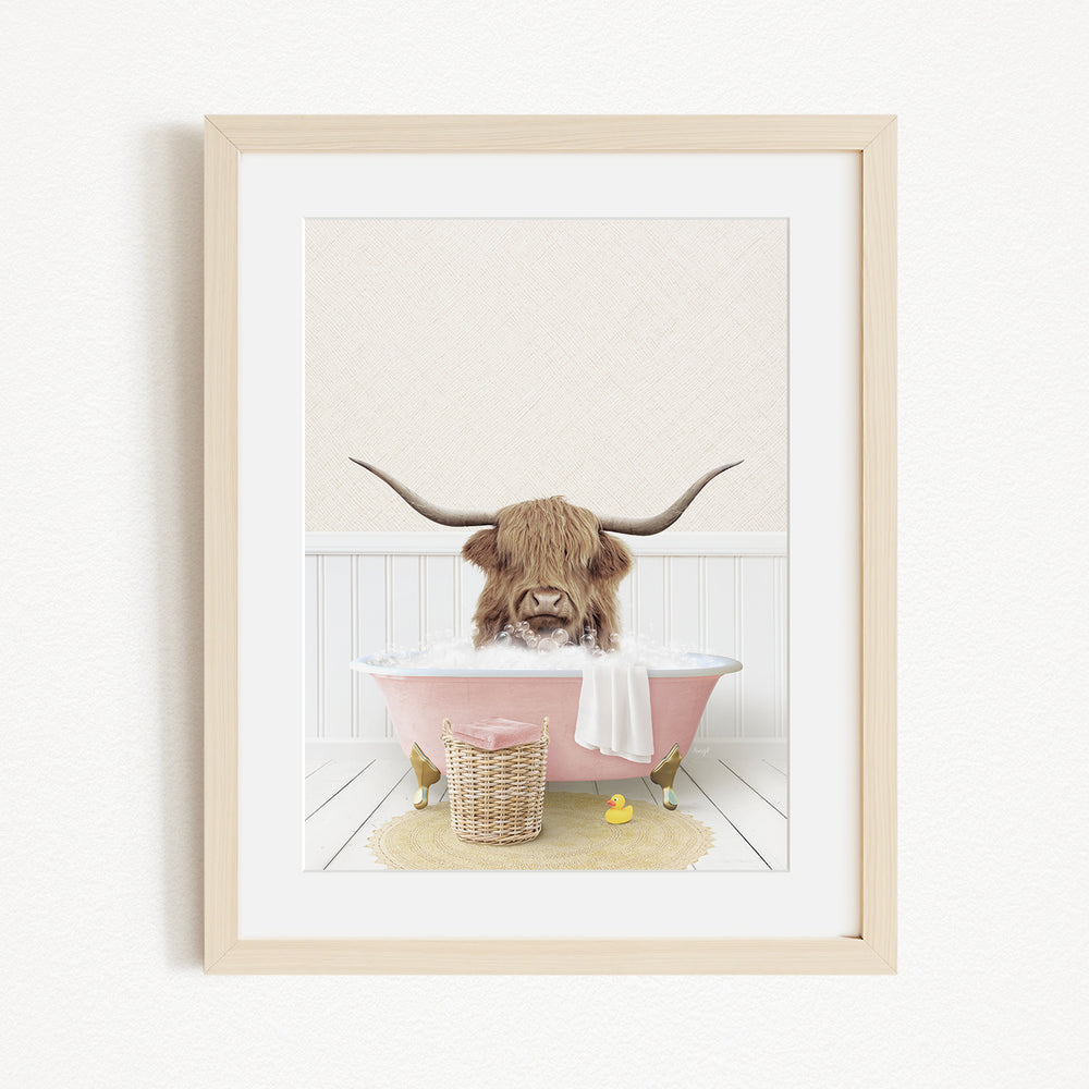 A Highland cow with large horns is sitting in a pink bathtub, surrounded by a yellow rubber duck and a basket.