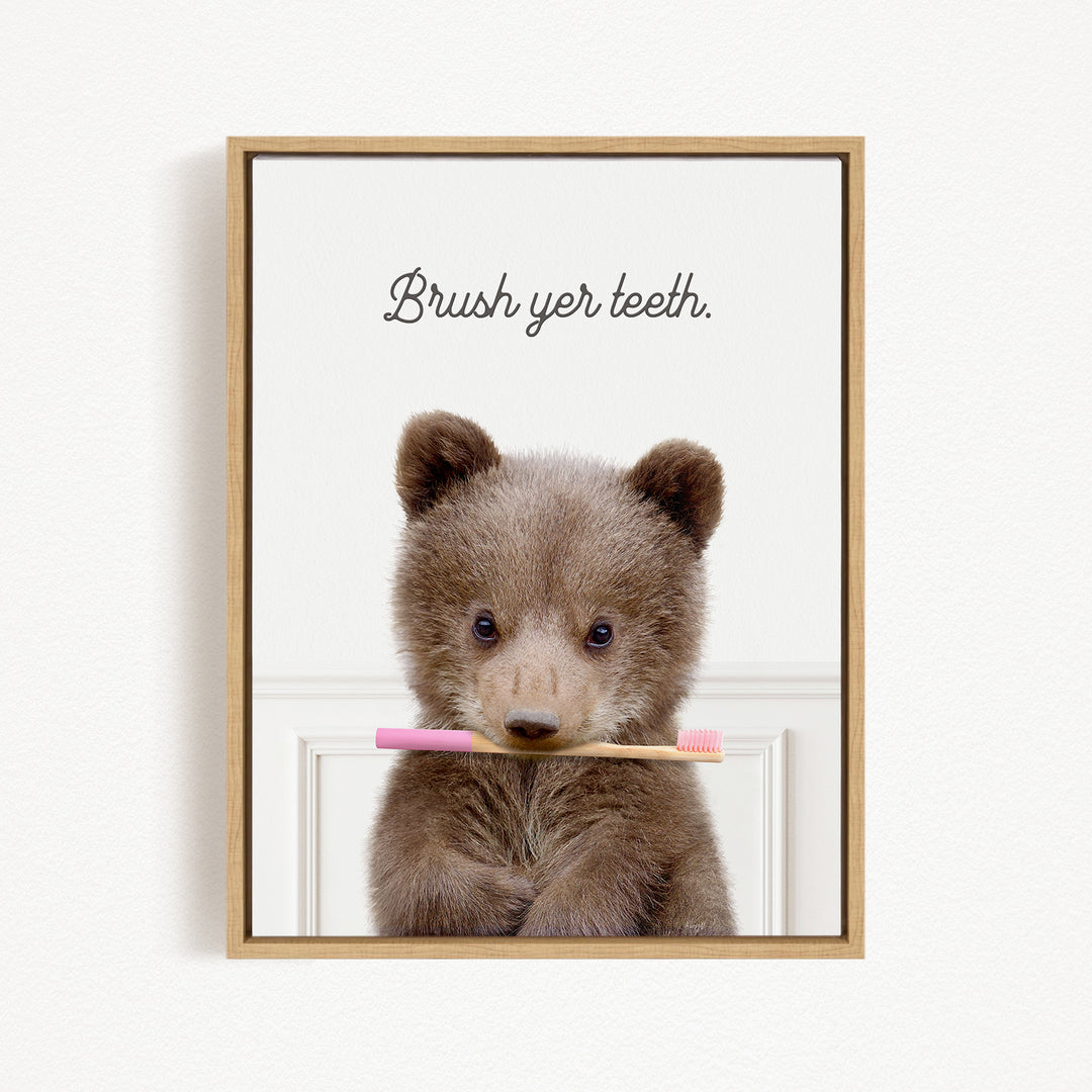A cute brown bear holding a pink toothbrush in its mouth, with the text "Brush yer teeth" above it.