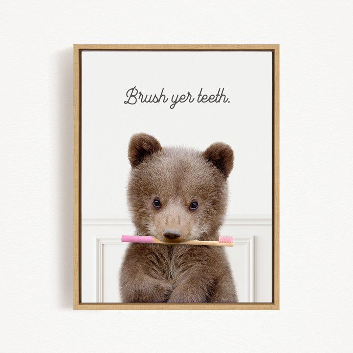 A cute brown bear holding a pink toothbrush in its mouth, with the text "Brush yer teeth" above it.