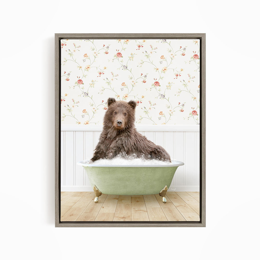 A brown bear sitting in a green bathtub filled with bubbles, with a floral wallpaper in the background.