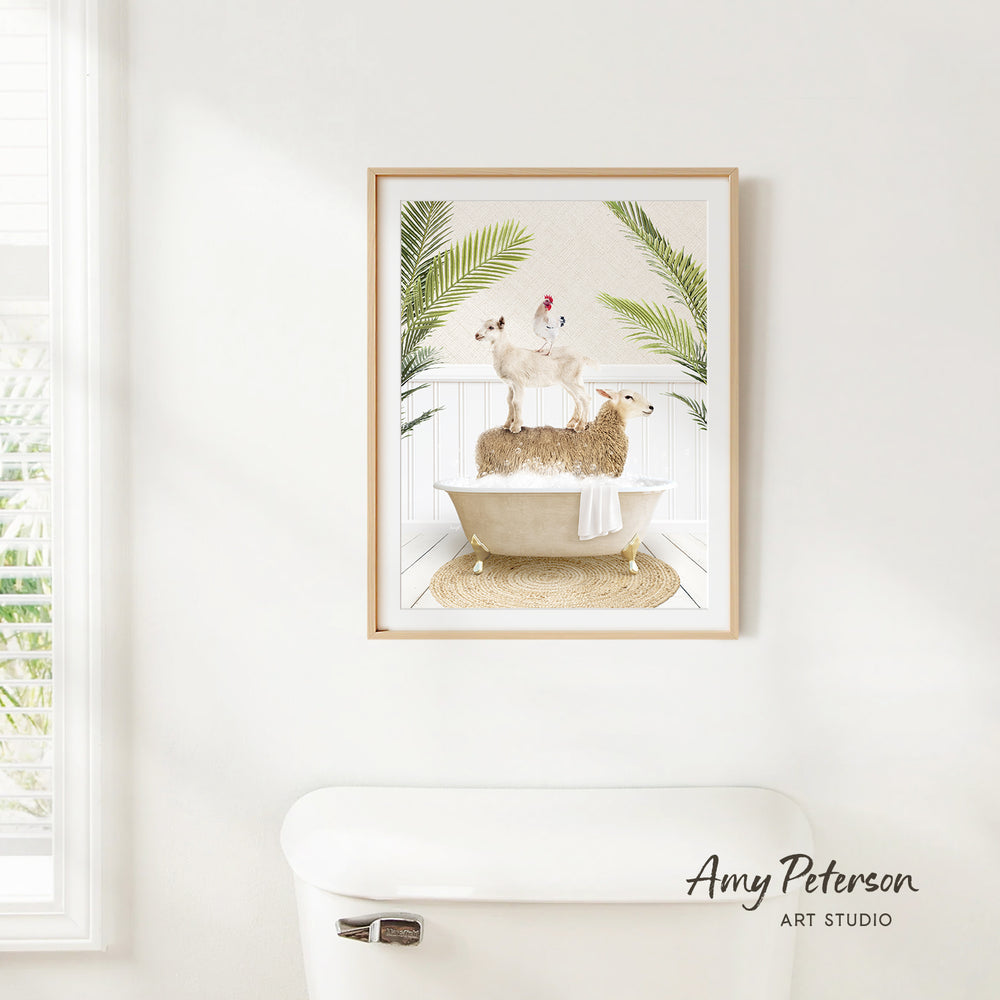 A framed print of a sheep standing in a bathtub, surrounded by palm leaves, is hanging on a white wall in a bathroom.