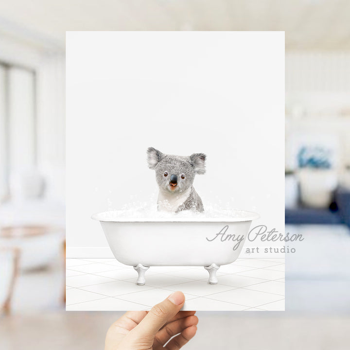 a hand holding a card with a picture of a koala in a bathtub