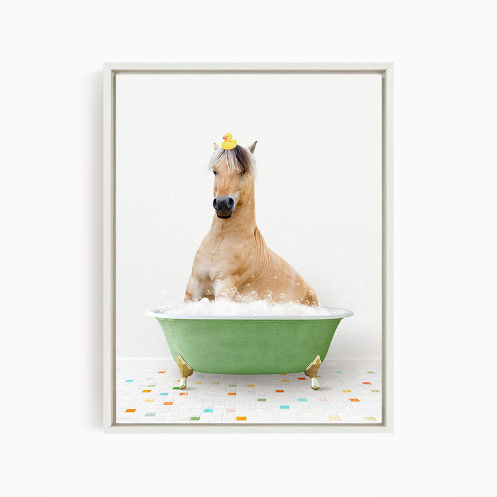 A light brown horse is sitting in a green bathtub filled with bubbles, wearing a yellow rubber duck on its head.