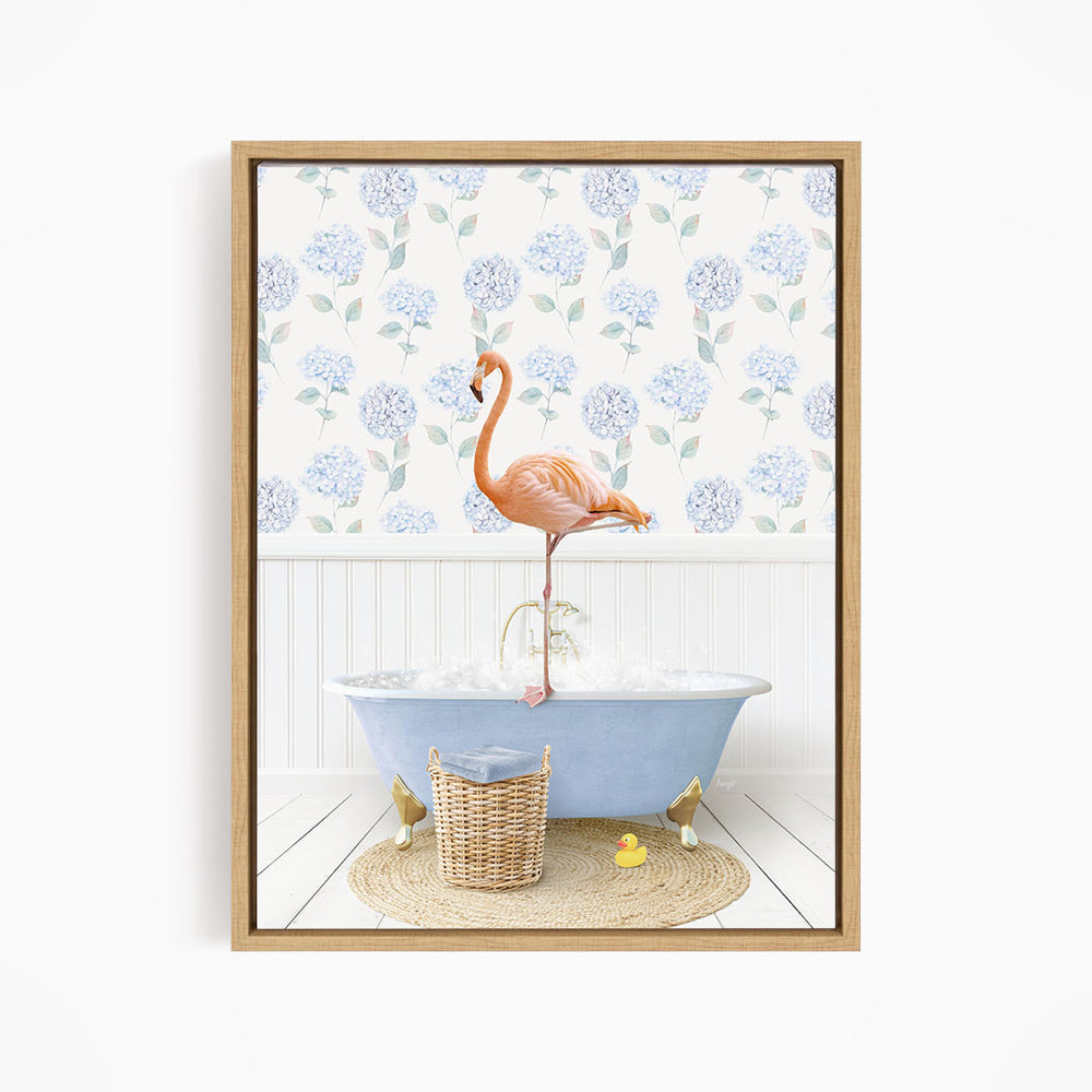 A pink flamingo stands on the edge of a blue bathtub, surrounded by a wicker basket, a yellow rubber duck, and a floral patterned wall behind it.