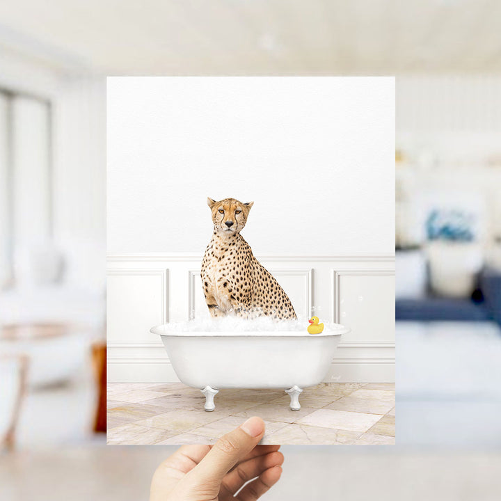 A cheetah sitting in a white bathtub filled with water and bubbles, with a rubber duck floating in the water.