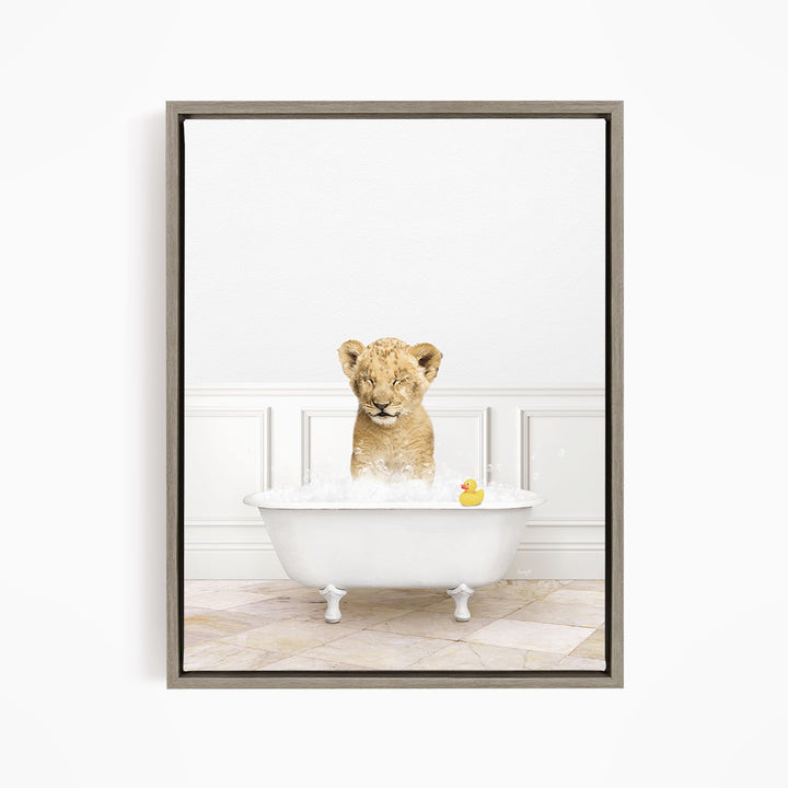 A young lion cub sitting in a white bathtub filled with water, with a rubber duck floating nearby.