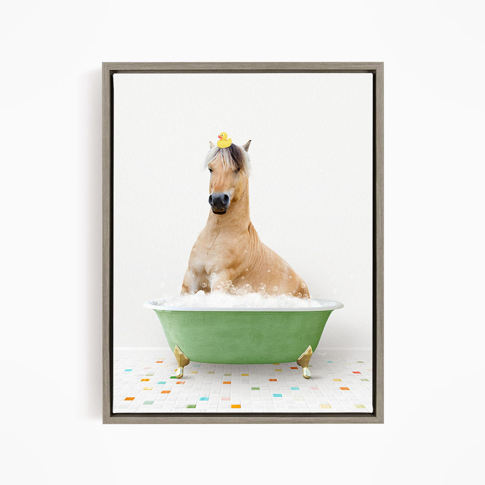 A light brown horse is sitting in a green bathtub filled with bubbles, wearing a yellow rubber duck on its head.