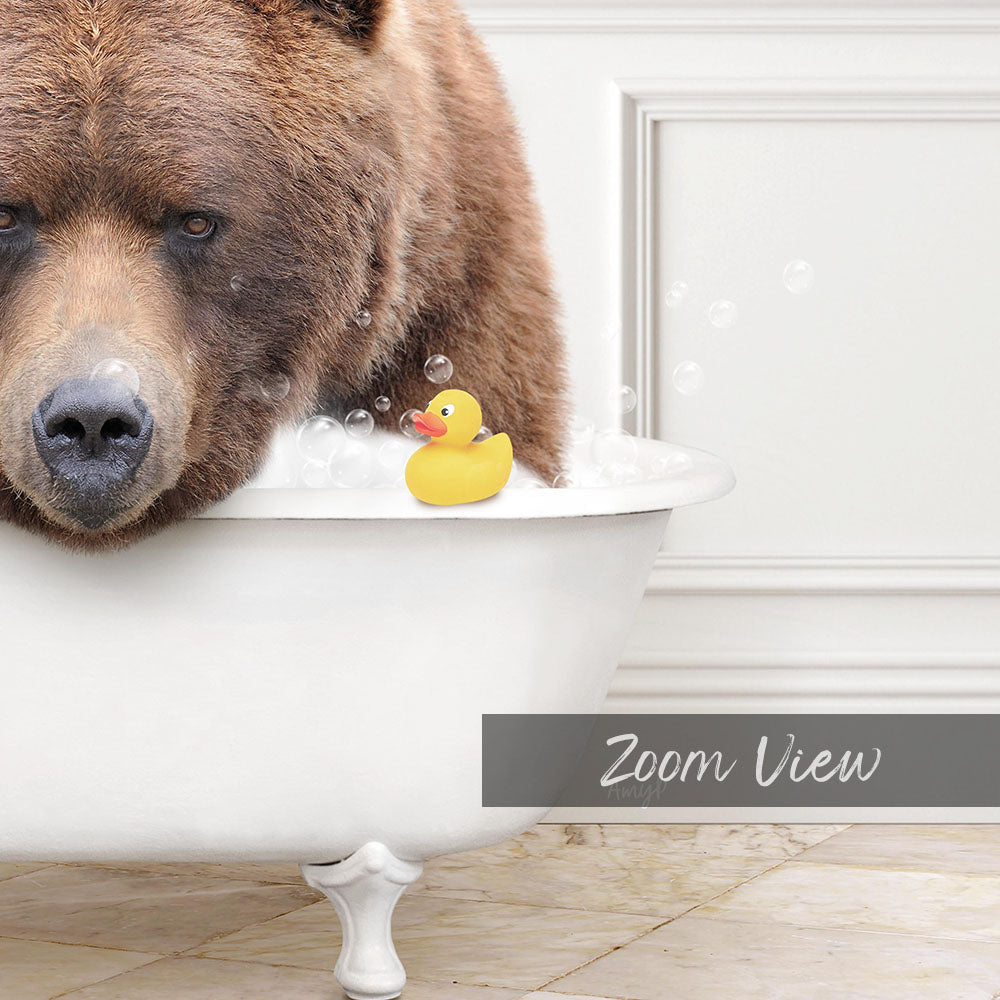 A large brown bear is sitting in a white bathtub filled with bubbles, with a yellow rubber duck floating on the water.