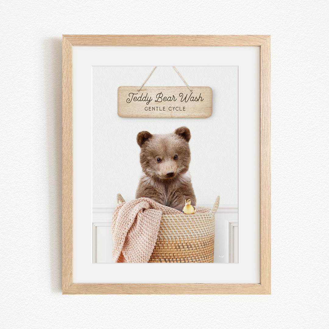 A framed image of a teddy bear sitting in a woven basket, with a sign above it that reads "Teddy Bear Wash Gentle Cycle".