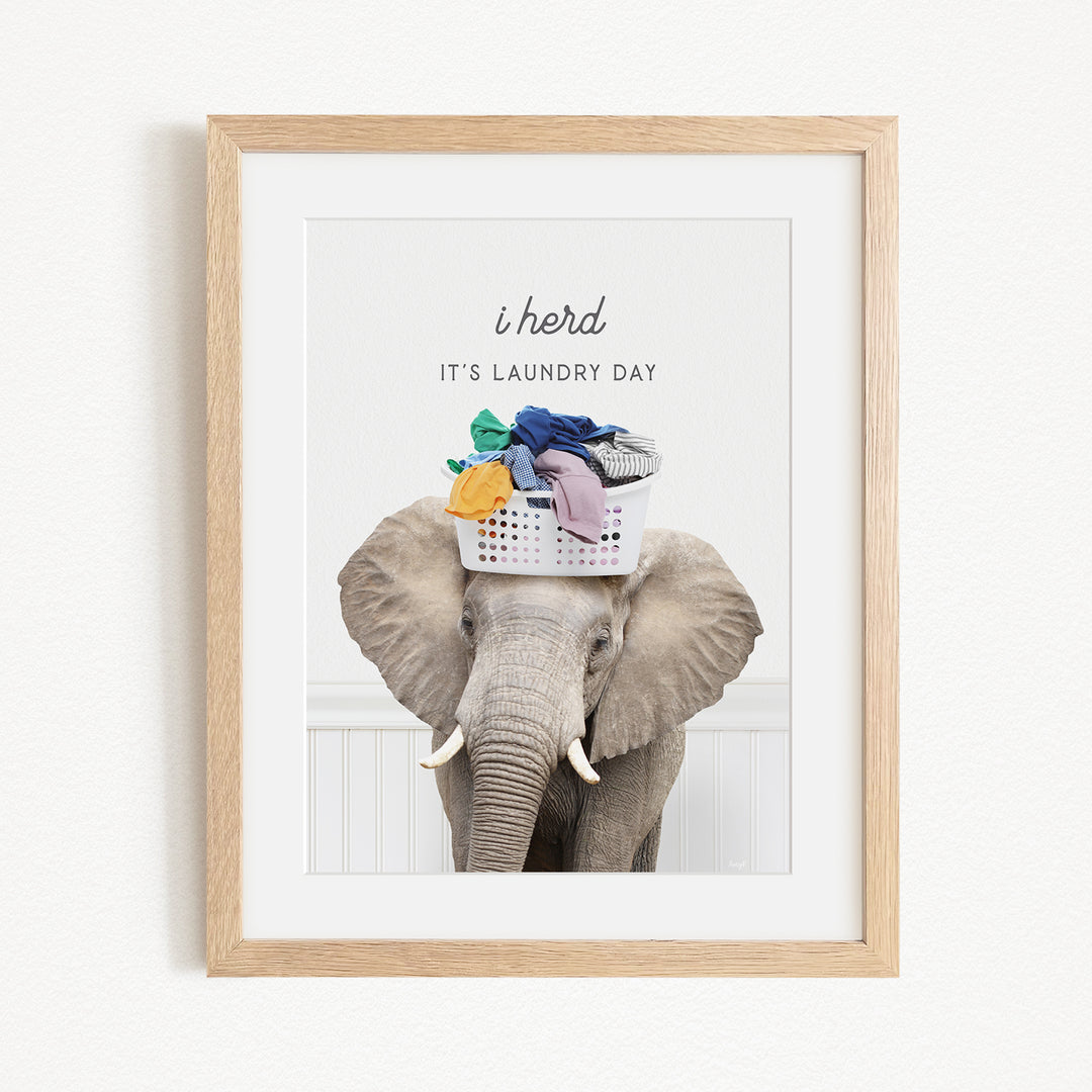 A framed image of an elephant holding a basket of laundry, with the text "It's laundry day" written above it.