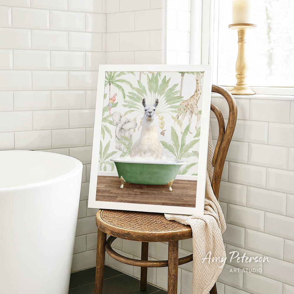 A framed print of a llama sitting in a green bathtub is displayed on a wooden chair in a bathroom setting.