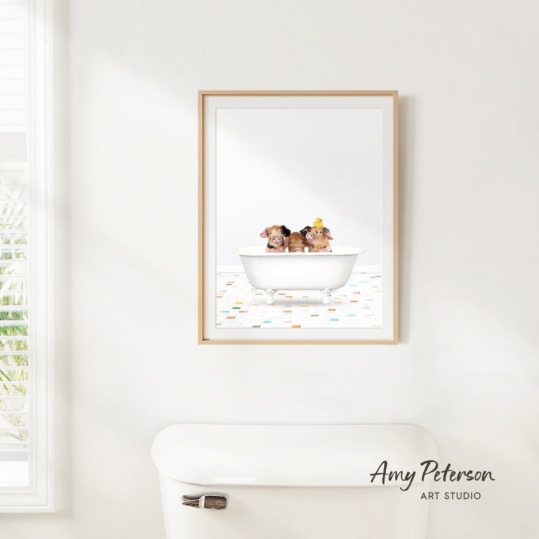 A framed print of two dogs sitting in a bathtub is hanging on a white wall above a white toilet.