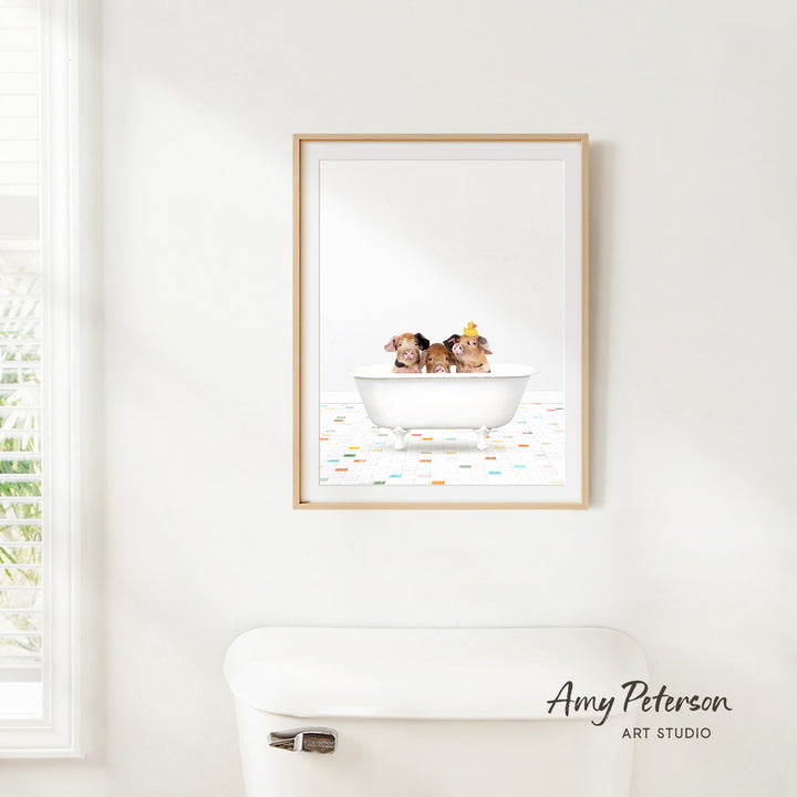 A framed print of two dogs sitting in a bathtub is hanging on a white wall above a white toilet.