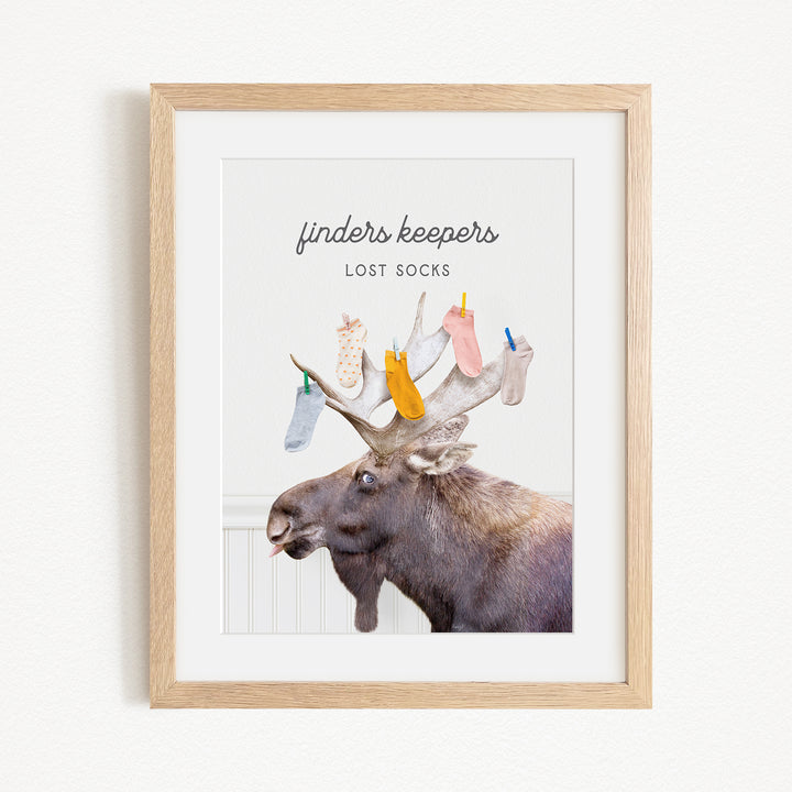 A framed image of a moose with a pile of colorful socks on its head, accompanied by the text "finders keepers lost socks"