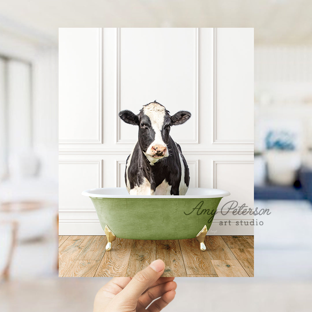 a hand holding a card with a picture of a cow in a bathtub