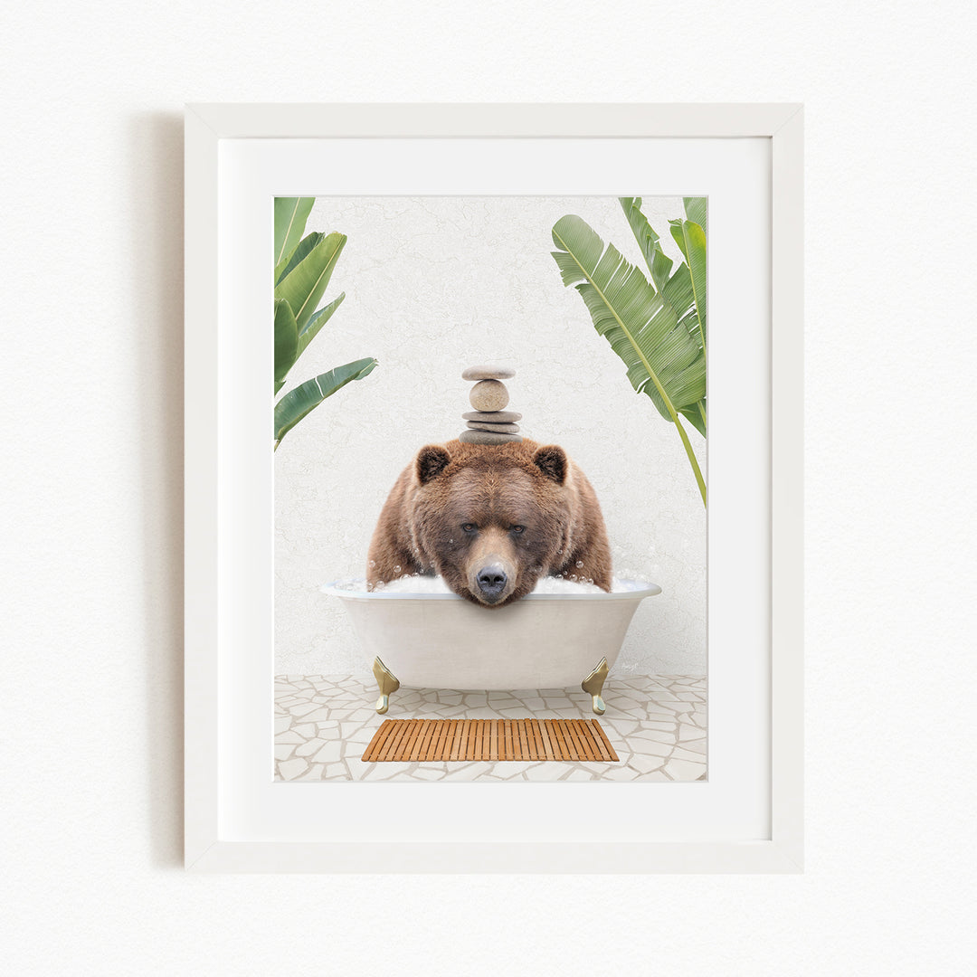 A brown bear is sitting in a white bathtub filled with water, surrounded by green plants and a wooden mat on the floor.