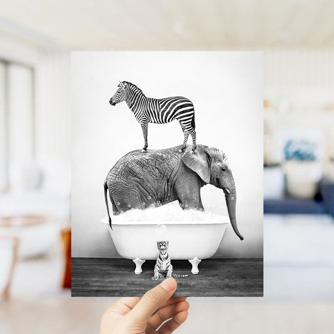 A hand holds up a black and white photograph depicting a zebra standing on an elephant's back while both animals are in a bathtub filled with water.