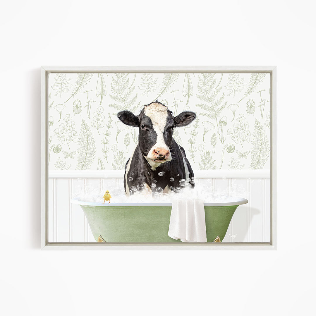 A black and white cow is sitting in a green bathtub filled with bubbles, with a small yellow bird perched on the edge of the tub.