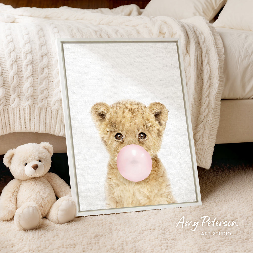 A framed image of a teddy bear blowing a bubble gum bubble next to a picture of a baby lion.