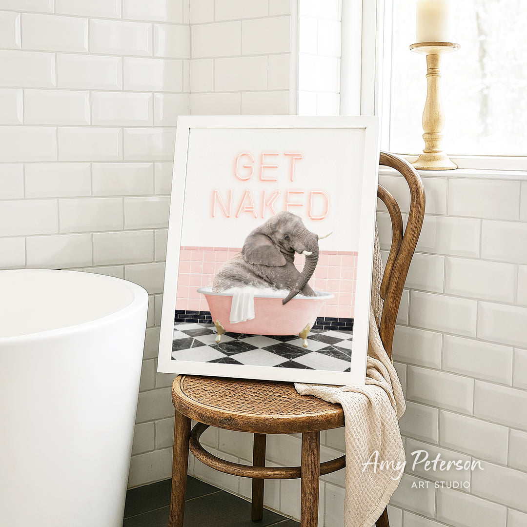 A framed image of a gray elephant sitting in a pink bathtub, with the text "GET NAKED" displayed on the frame.