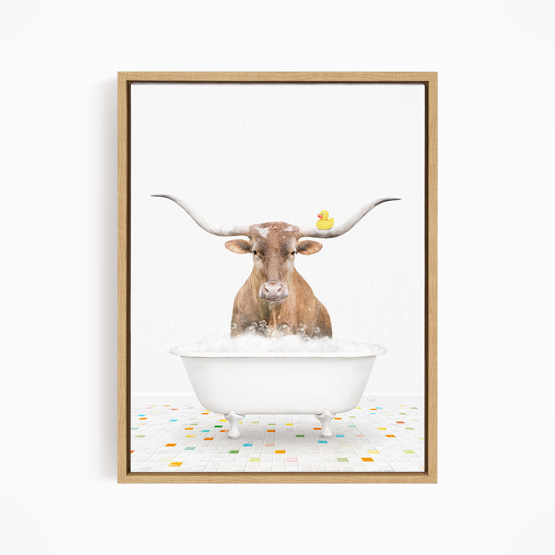 A brown cow with large horns is standing in a white bathtub filled with bubbles, with a yellow rubber duck floating on the water.