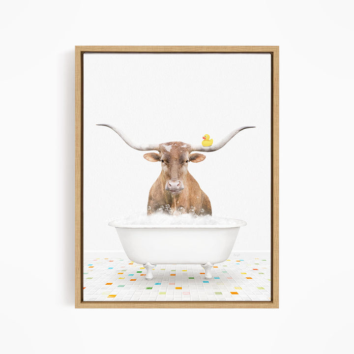 A brown cow with large horns is standing in a white bathtub filled with bubbles, with a yellow rubber duck floating on the water.