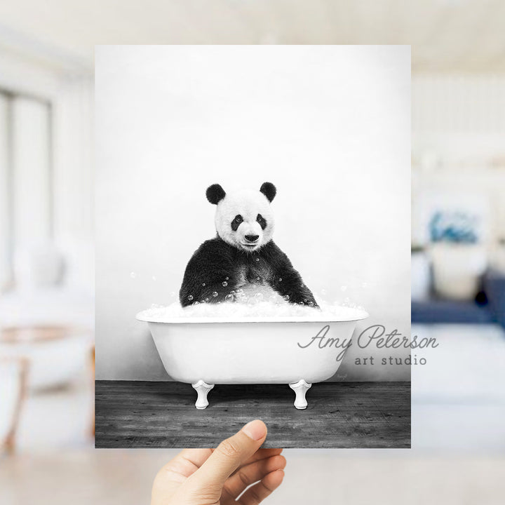 a hand holding up a black and white photo of a panda in a bathtub