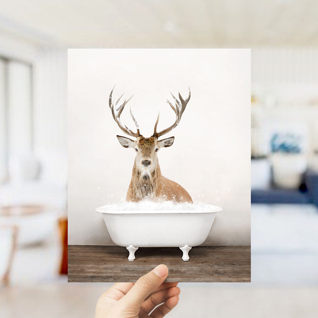 A deer with large antlers is sitting in a white bathtub filled with water, creating a whimsical and unexpected scene.