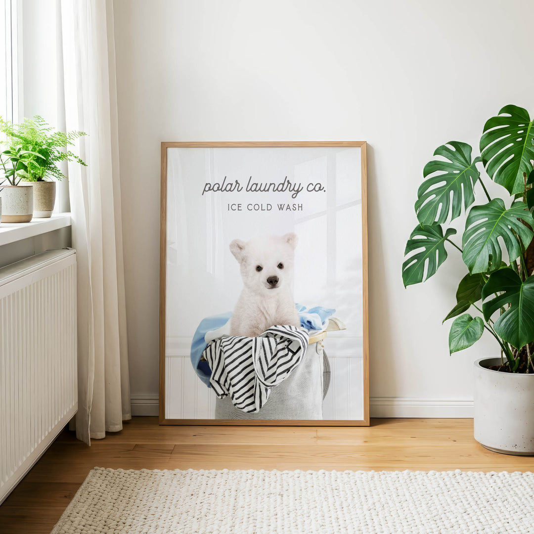 A framed poster of a polar bear sitting in a laundry basket, with the text "polar laundry co. ICE COLD WASH" displayed on it.