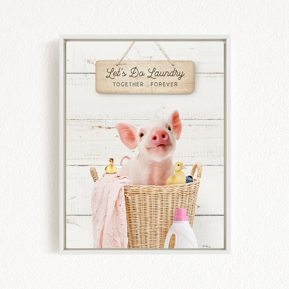 A cute pig sitting in a wicker basket filled with various toys, including a yellow duck and a pink blanket, with a wooden sign above that says "Let's Do Laundry Together Forever".