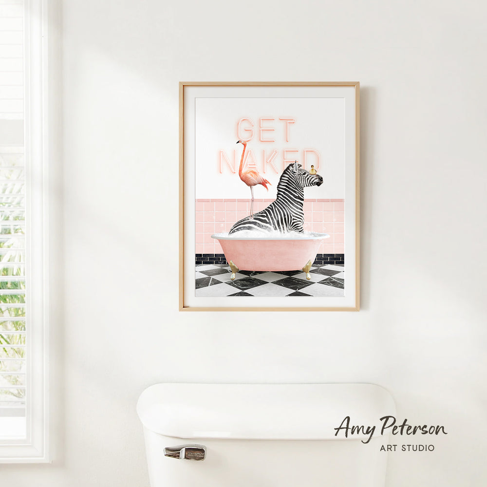 A framed print of a zebra sitting in a pink bathtub, with a flamingo standing on the edge of the tub, is hanging on a white wall.