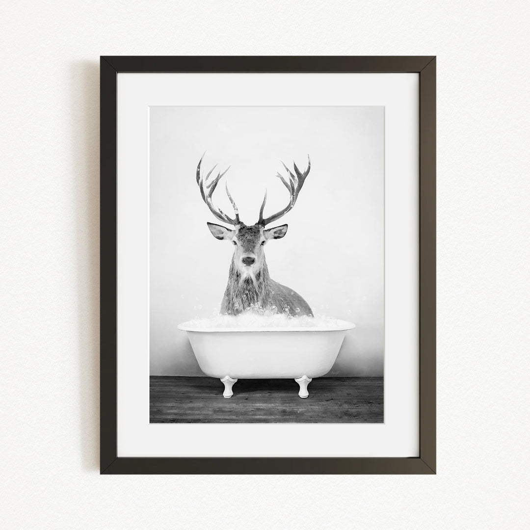 A deer with large antlers is sitting in a white bathtub filled with water, creating a whimsical and unexpected scene.