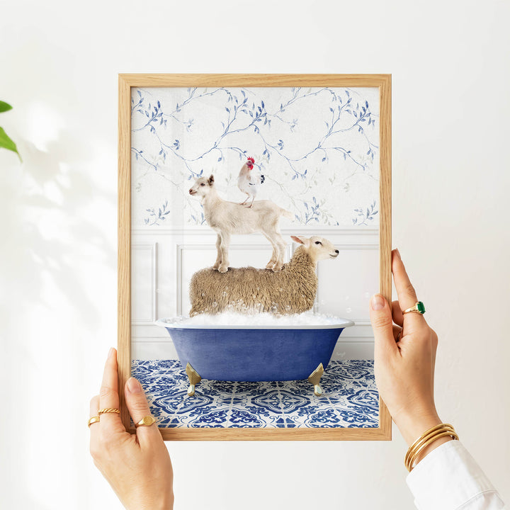 A person's hands are holding a framed image that depicts a sheep standing on a sheep in a bathtub, with a chicken perched on top of the sheep.
