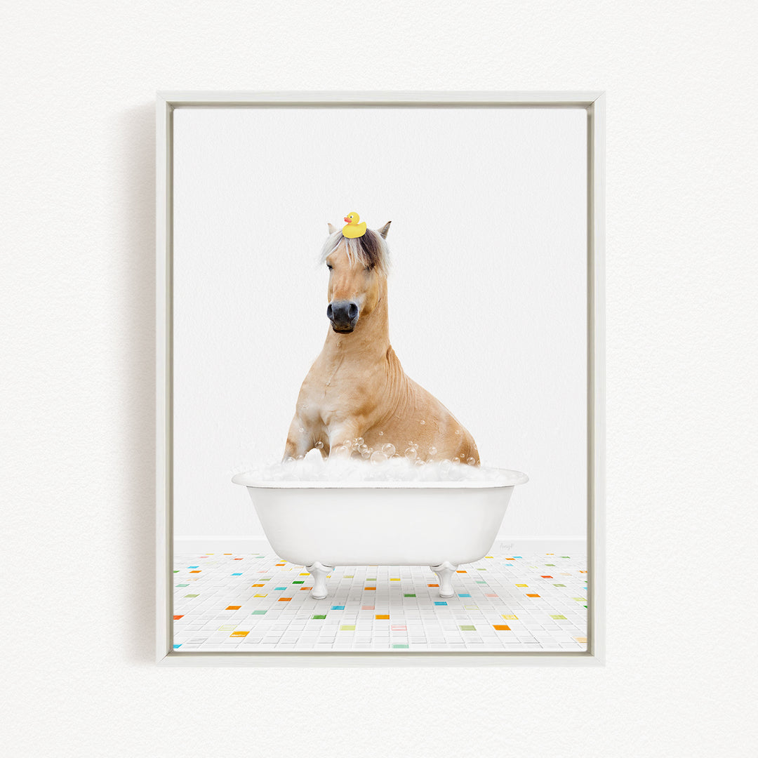 A light brown horse is sitting in a white bathtub filled with bubbles, with a yellow rubber duck perched on its head.