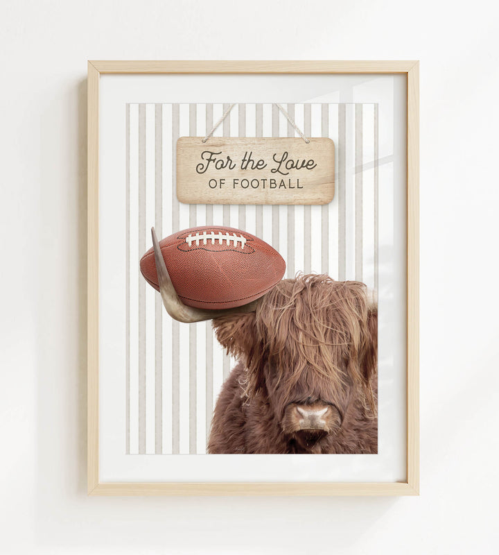 A framed image of a Highland cow with a football on its head, accompanied by a wooden sign that reads "For the Love of Football".