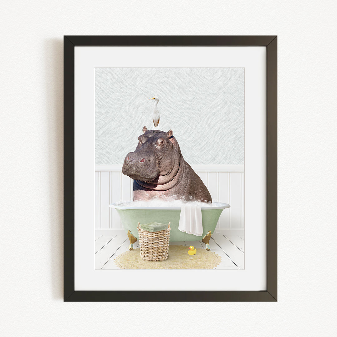 A framed image depicting a hippopotamus sitting in a bathtub, with a bird perched on its head.
