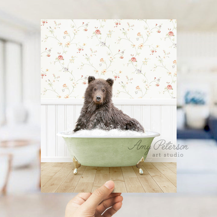 a hand holding up a photo of a dog in a bathtub