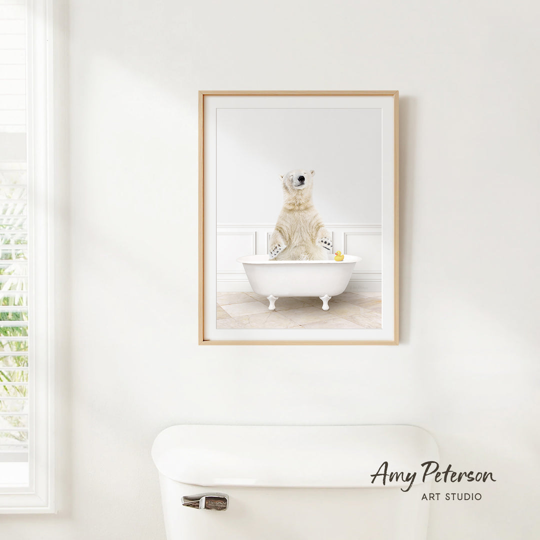 A framed image of a polar bear sitting in a bathtub, with a window and toilet visible in the background.