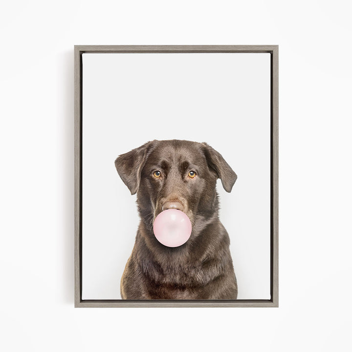 A brown dog is blowing a bubble with a pink bubble gum bubble.